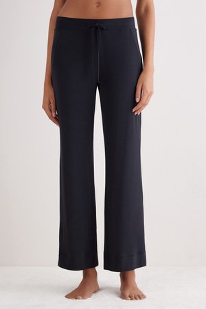 Pantalons de lounge noirs à large jambe avec une taille à cordon de serrage, présentant une texture lisse et un ourlet à revers. Adaptés pour un usage décontracté.