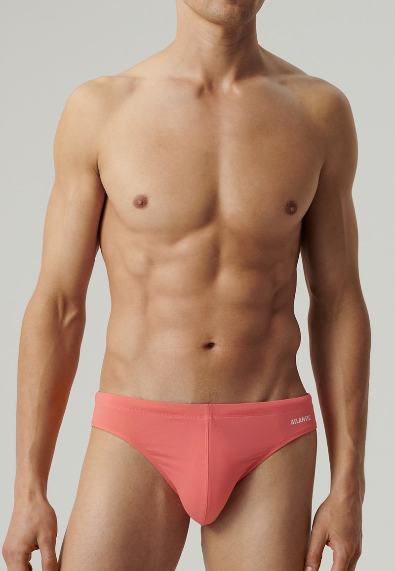 Koralowy bikini w formie fig, wykonany z elastycznego materiału, charakteryzujący się gładką fakturą i markowym akcentem na pasku.