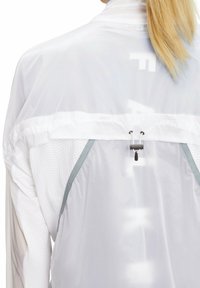 Witte lichtgewicht jas met een mesh binnenlaag, ronde halslijn, verstelbare zoom met trekkoord en grijze accenten op de schouders.