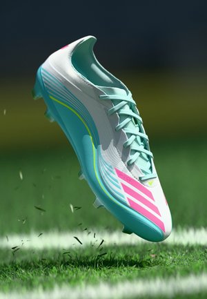 Un botín de fútbol en azul claro y blanco con acentos en rosa y verde, que presenta un diseño aerodinámico, parte superior texturizada y suela con tacos.