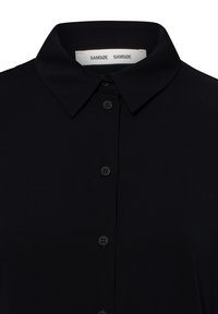 Zwarte shirt met kraag, knopen aan de voorkant en een wit label binnenin de kraag met de merknaam Samsøe Samsøe.