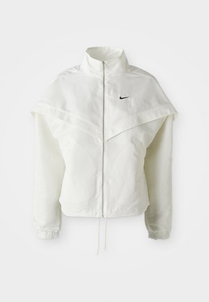 Witte lange mouwen zip-up jas met hoge kraag, cape-achtige details over de schouders, elastische manchetten en een klein zwart Nike-logo op de borst.