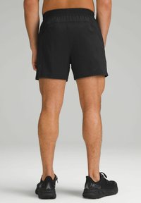 Black athletic shorts with an elastic waistband, featuring a smooth texture and short length. Paired with black running shoes.