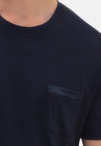 Marineblauw katoenen t-shirt met een ronde halslijn en een borstzak met een satijnen afwerking. Zachte textuur en een standaard pasvorm.