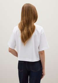 Witte cropped t-shirt met korte mouwen, ronde hals en een gladde katoenstructuur. Draag het met donkerblauwe high-waisted jeans.