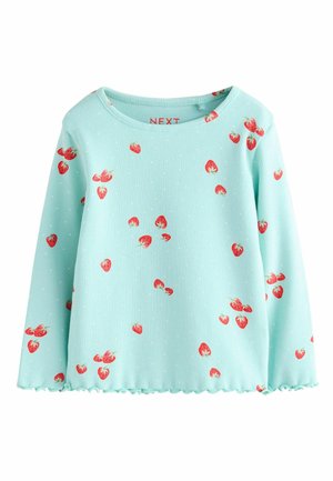 Gaiši zilā ribota garroku blūze ar izkliedētām sarkanu zemeņu drukām un mazām baltām punktotām vietām; malai ir viļņota apmale, kas piešķir detaļas.