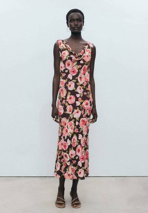 Floral dress featuring a cowl neckline, dark fabric with large pink and green flowers, knee-length, complemented by simple brown sandals.