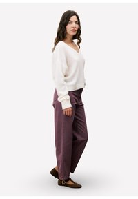 Romige, fuzzy gebreide trui met V-hals; high-waisted, paarse wijde broek; bruine ballerina's met een gesp.