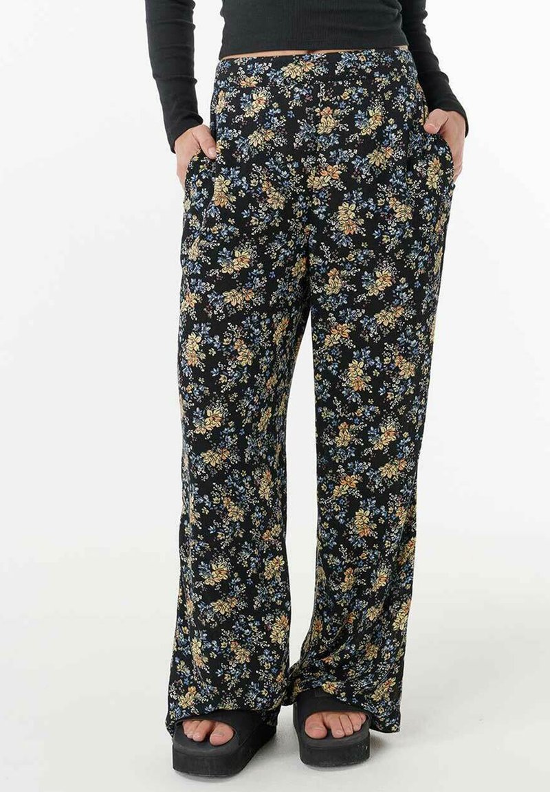 Pantalons fluides noirs à fleurs avec un mélange de fleurs jaunes, bleues et blanches. Ils offrent une coupe décontractée et des poches latérales pour plus de fonctionnalité.