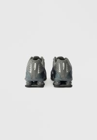 Γκρι αθλητικά παπούτσια με υφή πλέγματος και γυαλιστερές λεπτομέρειες. Διαθέτουν ελαστική σόλα για απορρόφηση κραδασμών, σχεδιασμένα για απόδοση.