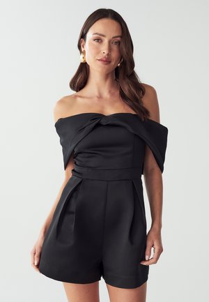Zwarte off-shoulder rompert gemaakt van satijn, met een geknoopt lijfje, gestructureerde taille en geplooide shorts.