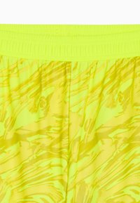 Pantaloni corti giallo neon con un motivo testurizzato e ondulato. Vita elasticizzata con arricciatura, realizzati in materiale leggero e traspirante.