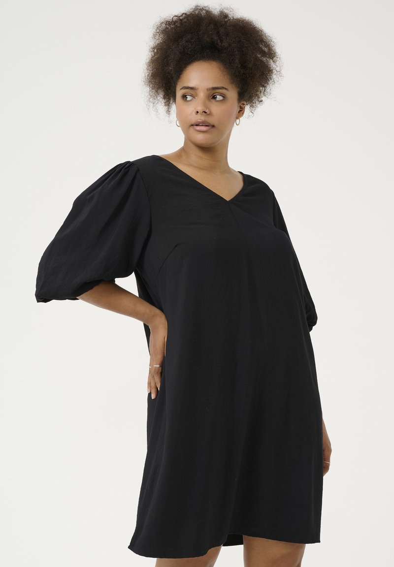 Robe noire avec un décolleté en V et des manches bouffantes, fabriquée en tissu léger. Le design est ample avec une silhouette droite.