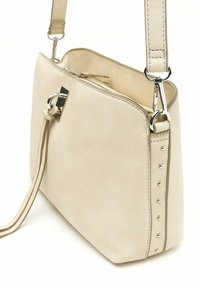 Bežna teksturirana torba z gladko površino, ki ima srebrno kovinsko zaponko, nastavljiv trak in okrasne konice ob eni strani.