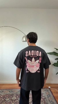 Tamsiai pilka per didelio dydžio marškinėliai su dideliu rožiniu grafiniu vaizdu dubenėlio ramen su lazdelėmis ir užrašu „ADIDAS“ ant nugaros.
