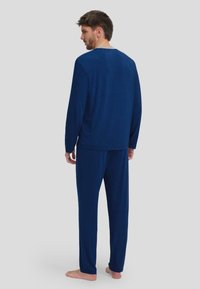 Conjunto de pijama azul marino de tejido suave que incluye una camiseta de manga larga y pantalones a juego, con cuello redondo y un corte holgado.