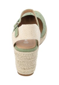 Sandalia cuña de esparto verde y beige con tacón de yute trenzado. Presenta una amplia tira de tela con un patrón de cuadros y una hebilla lateral.