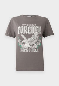 T-shirt en coton gris arborant un grand graphisme d'un aigle et de roses, avec le texte "TOUR MONDIAL POUR TOUJOURS ROCK & ROLL" en lettres blanches en gras.