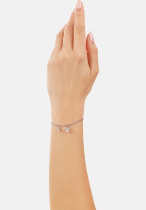 Bracciale in argento a catena con due accenti sferici. Texture liscia con un design delicato, indossato su una mano su uno sfondo neutro.