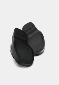 Calzature nere con finitura liscia, suole testurizzate e design minimalista. Presentano aree imbottite per comfort e aderenza.
