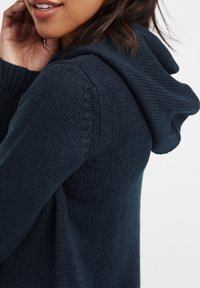 Navyblå stickad tröja med huva, med texturerad tyg och avslappnad passform, som har sidoklyftor för enkel rörlighet.