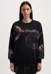 Zwarte sweatshirt met kleurrijke zwirlpatronen, een ronde hals en geribde manchetten. De voorkant toont de tekst "Unite Forever" in een lichte lettertype.