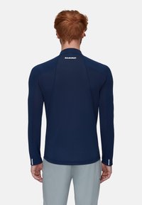 Navy Langarmshirt aus Stretchstoff, mit tailliertem Design, flachen Nähten und Logo am Nacken hinten. Akzente an den Bündchen.