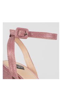 Sandal con tacco alto glitterato rosa, dotata di una fascia alla caviglia testurizzata con fibbia quadrata, soletta rosa liscia e design della punta arrotondata.