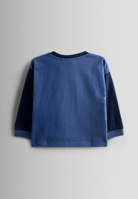 Maglia a maniche lunghe blu con girocollo, con il corpo di un blu più chiaro e le maniche di un blu più scuro. Materiale in cotone morbido con una superficie liscia.