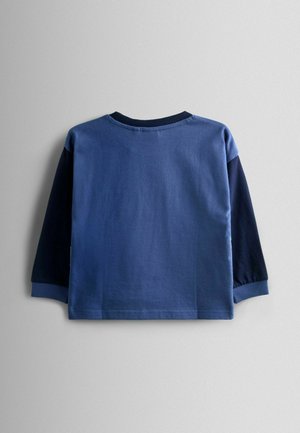 Kék crewneck hosszúujjú póló, világoskék testtel és sötétebb kék ujjal. Puha pamut anyag, sima textúrával.