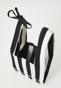 Black and white striped fabric bag with a square shape, featuring a tied handle, and text detail at the bottom. Soft, textured material.