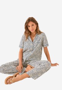 Geprinte tweedelige lounge set met korte mouwen, een knoopsluiting overhemd en cropped broek in een crème en marineblauw geometrisch patroon.