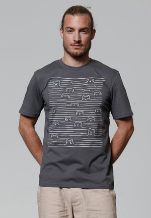 Graues T-Shirt mit kurzen Ärmeln, das ein weißes, lineares Hundemuster an der Vorderseite zeigt. Der Stoff wirkt glatt und hat eine lässige Passform.