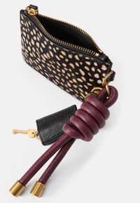 Wzorzysta saszetka w czarno-beżowej skórze z futra, z złotym zamkiem. Posiada burgundowy skórzany uchwyt oraz małą czarną kieszonkę na klucze przymocowaną.