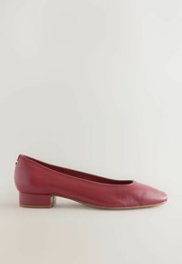 Bailarina de cuero rojo con punta redonda y tacón cuadrado bajo. Textura suave con una silueta simple y un detalle mínimo.