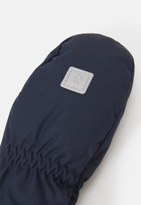 Marineblaue Handschuhe aus strukturiertem Stoff, mit elastischem Bündchen und einem kleinen grauen Quadrat-Patch mit einem Logo. Glatte, isolierte Oberfläche.