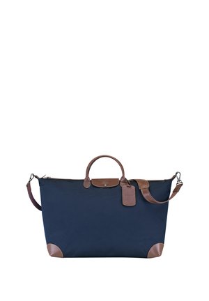 Navy blue fabric tote bag with brown leather accents, a top handle, detachable shoulder strap, and a luggage tag attached.