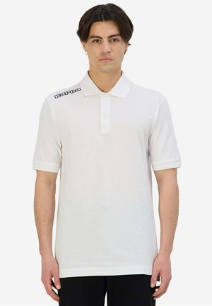 Polo bianco con colletto e patta con tre bottoni. Presenta il logo nero "Kappa" sulla spalla sinistra. Maniche corte con polsini arrotolati.