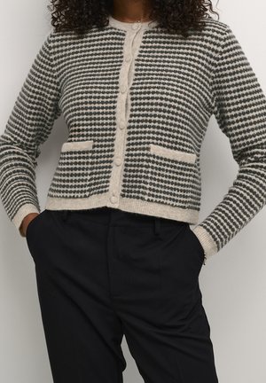 Cardigan en tricot noir et crème avec des rayures horizontales, présentant un col rond, des boutons à l'avant et deux poches avant.