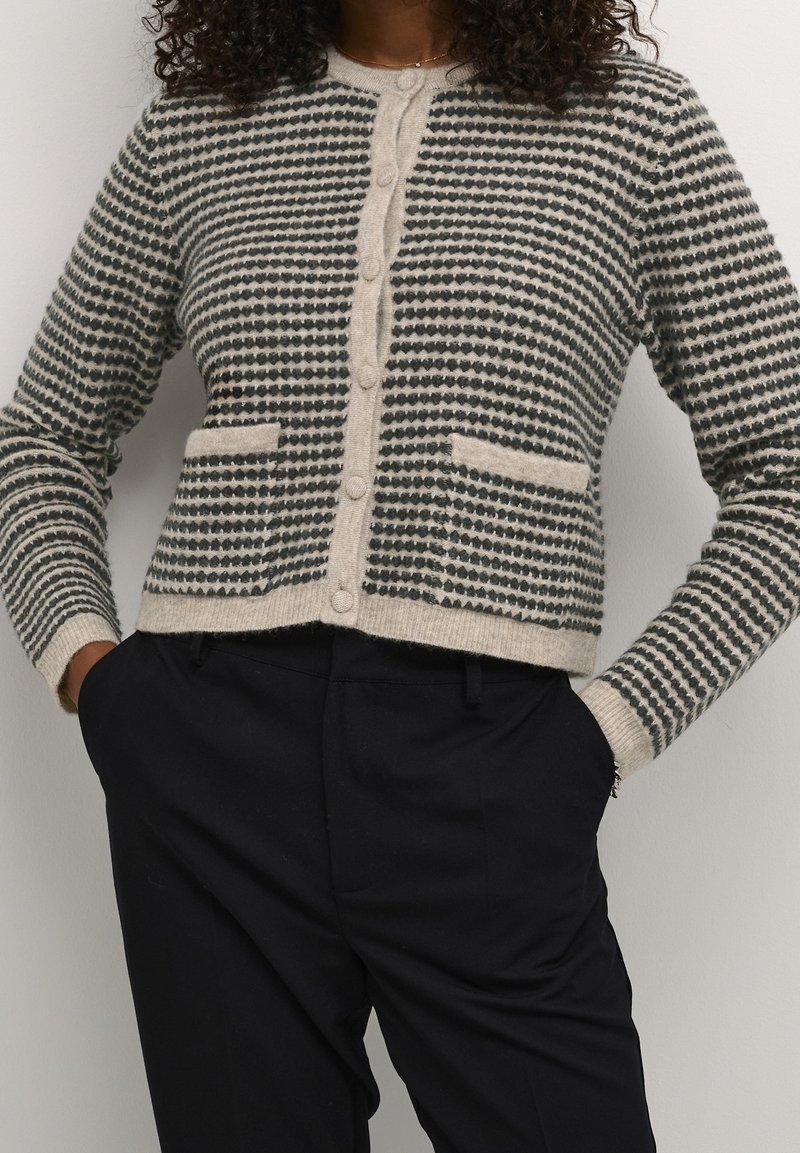 Cardigan lavorato a maglia in nero e crema con righe orizzontali, con scollo rotondo, bottoni frontali e due tasche frontali.