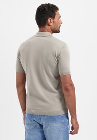 Lichtgrijze polo met korte mouwen, gemaakt van gestructureerde stof, met een gebreide kraag en zoom, gecombineerd met blauwe spijkerbroek shorts.