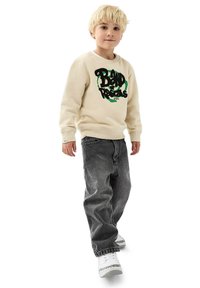Kermansweater med svart och grön grafisk tryck, kombinerad med avslappnade mörkgrå jeans och vita sneakers. Mjuk tyg, avslappnad design.