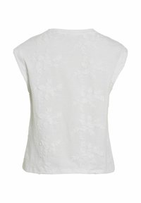 Camiseta de algodón blanca de manga corta, con bordado floral en relieve en la parte trasera, cuello redondo y un corte ligeramente holgado.