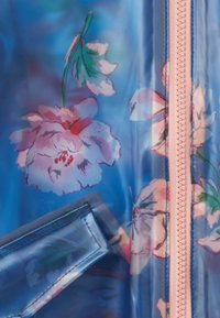 Transparent blå regnjacka med rosa blommönster, med en rosa dragkedja och fickdetalj. Slät textur och lättviktsdesign.