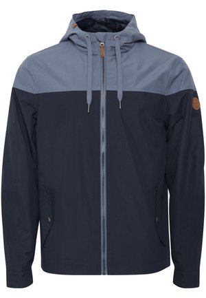 Granatowa i jasnoniebieska kurtka zapinana na zamek z kapturem, z kontrastowymi panelami kolorystycznymi, sznureczkami oraz detalem kieszeni bocznej.