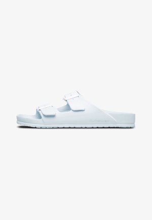 Sandalias casuales blancas de goma con dos correas ajustables. Presentan una plantilla texturizada y una suela ancha para mayor estabilidad.
