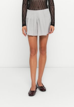 Gray pleated shorts made from a textured fabric, featuring a high waist and a relaxed fit, paired with glossy burgundy flats.