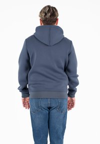 Sweat à capuche en mélange de coton bleu foncé, avec une poche kangourou et des poignets côtelés. Présenté dans une coupe décontractée avec une vue arrière.