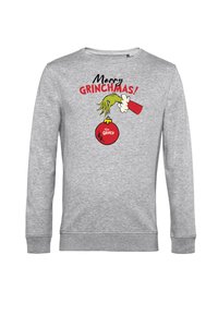 Sudadera gris con un gráfico colorido de una mano verde sosteniendo un adorno rojo, con el texto "¡Feliz GRINCHMAS!" arriba.