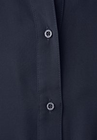 Close-up of a dark navy shirt front showing two plastic buttons labeled "Street One" with visible stitching on fabric.